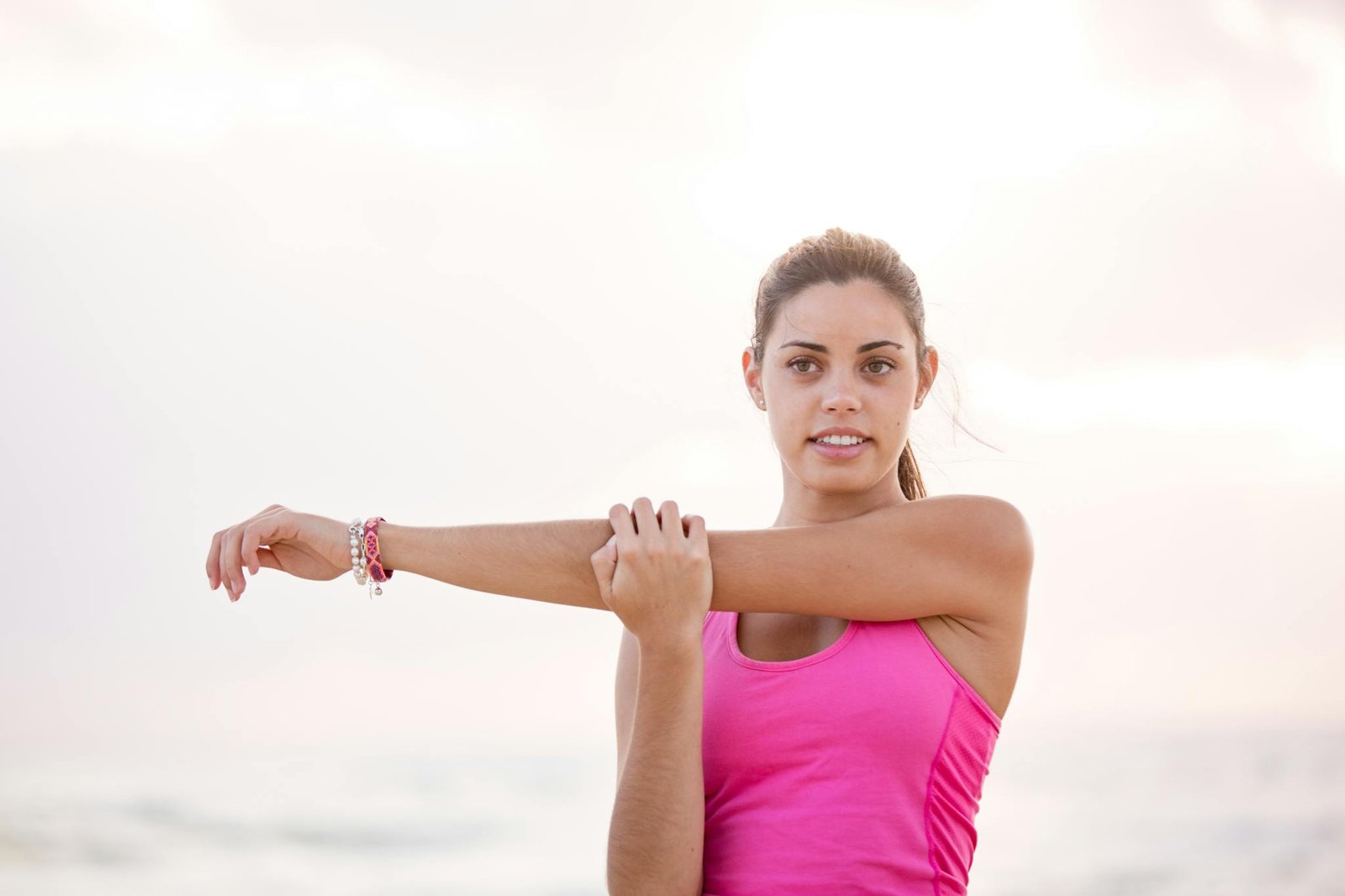 Young woman enjoying a relaxing stretch on a sunny Australian beach. Perfect for lifestyle and fitness themes.