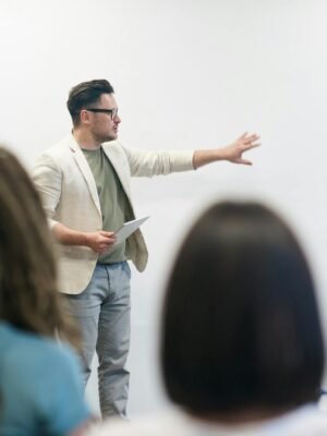 A man in a blazer gives a presentation to a captivated audience in a lecture setting.