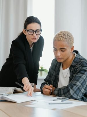 Focused study session with teacher mentoring student with textbooks indoors.
