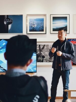 Man giving a presentation in a modern art gallery setting, engaging audience.
